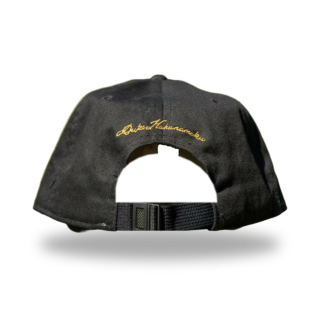 Back of black cap with gold Duke Kahanamoku signature embroidery above adjustable strap