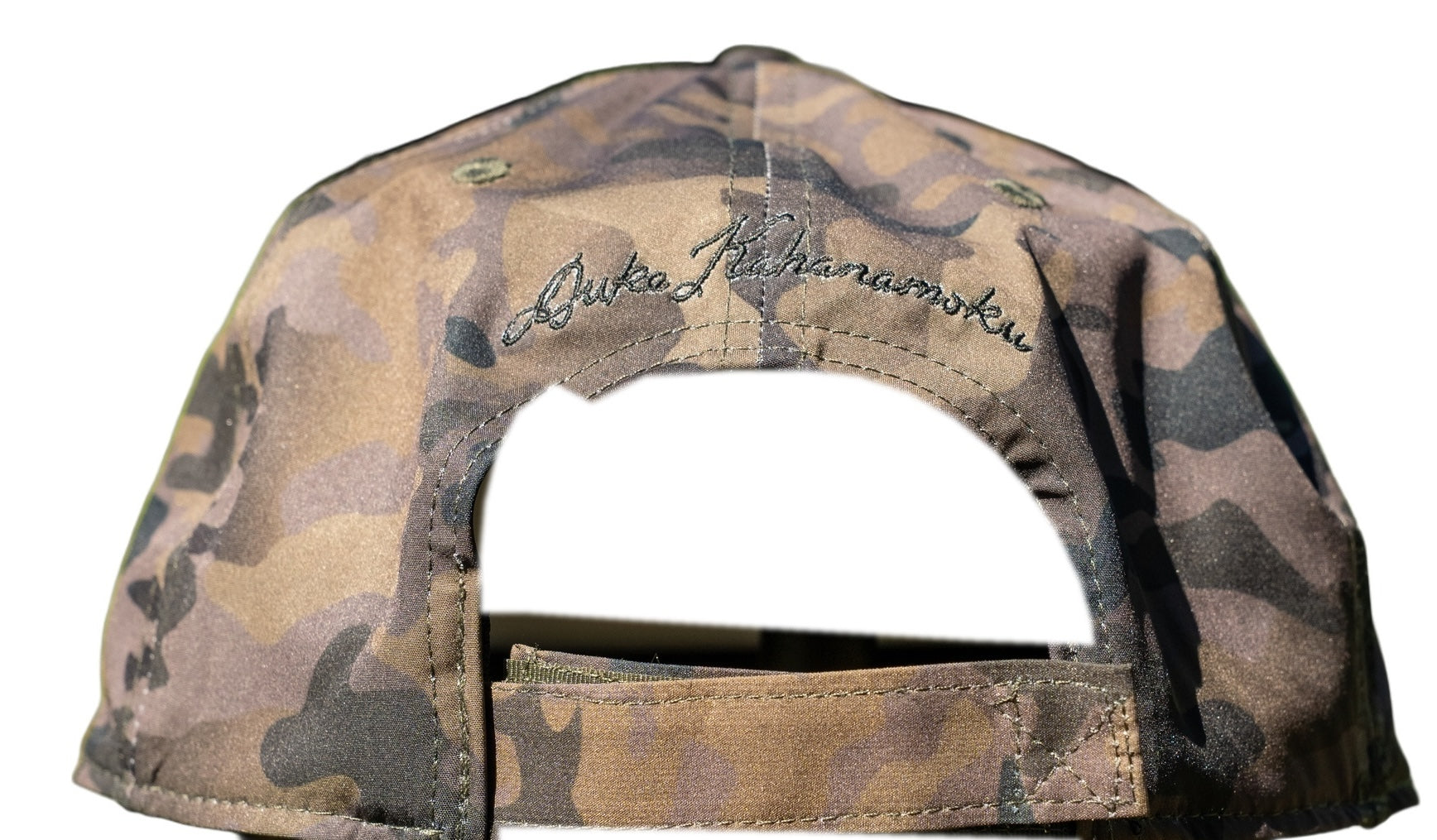 Back of camo snapback with Duke Kahanamoku signature embroidery above camo strapback closure