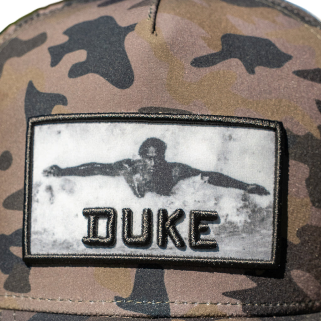 Close-up of woven swimmer photo patch with 3D black DUKE lettering on camo cap