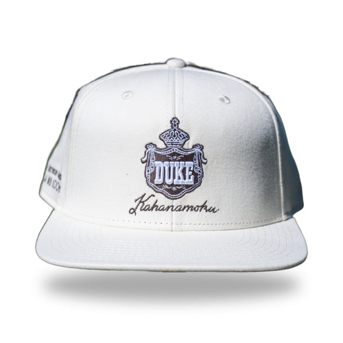 Cream snapback cap with brown embroidered Hawaiian royal crest reading DUKE and Kahanamoku script