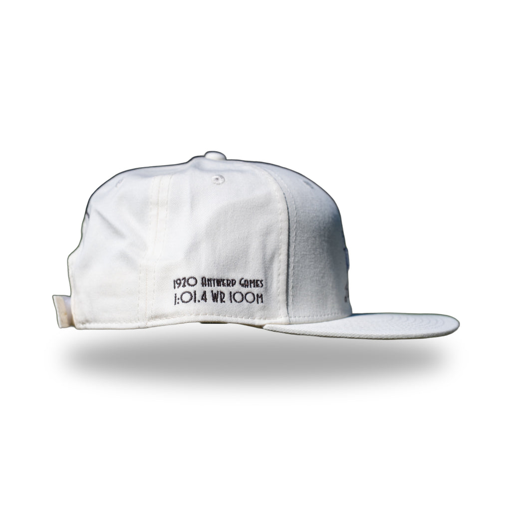 Side of cream DUKE cap showing 1920 Antwerp Games 1:01.4 WR 100M embroidery