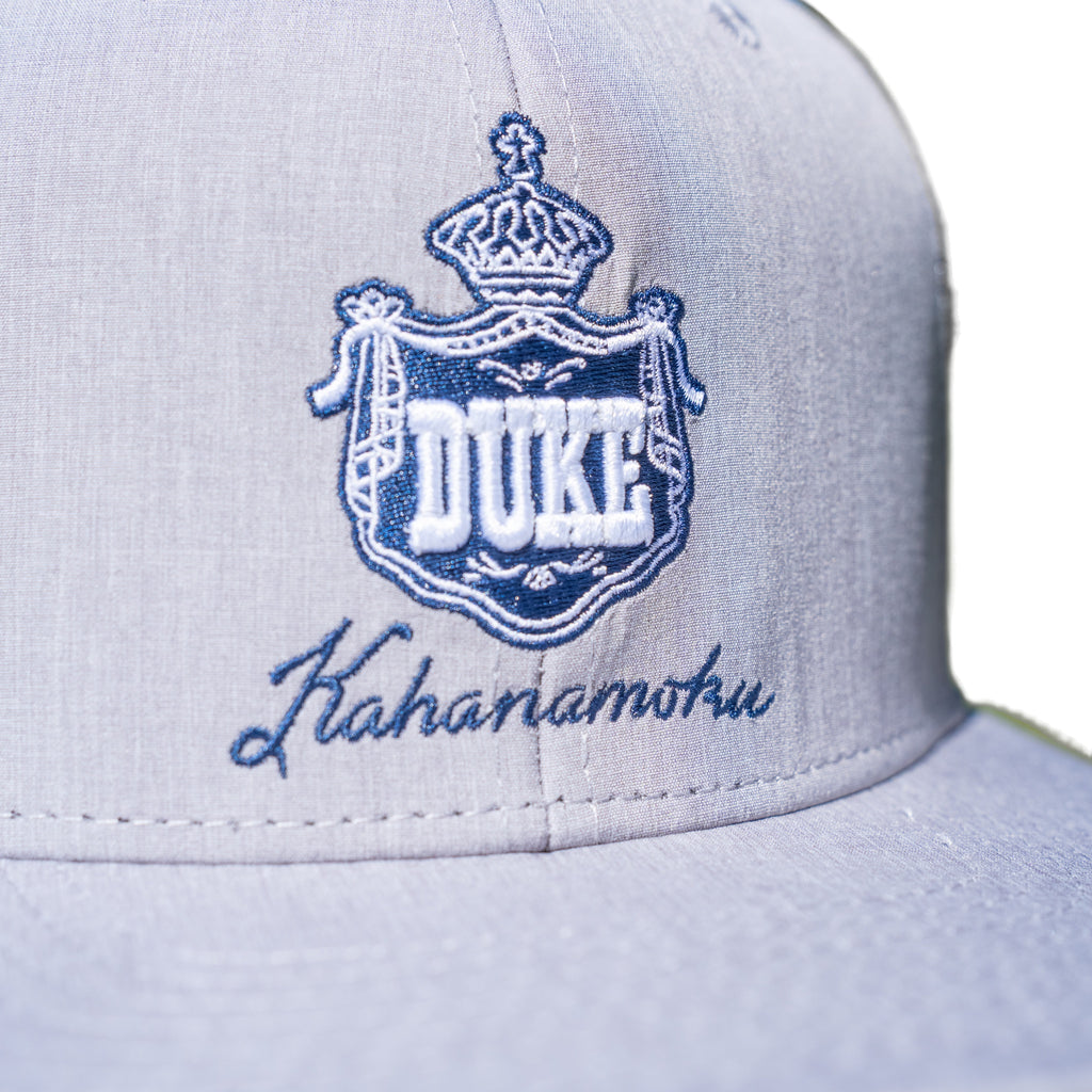 Close-up of navy and white DUKE royal crown crest embroidery on heather gray cap