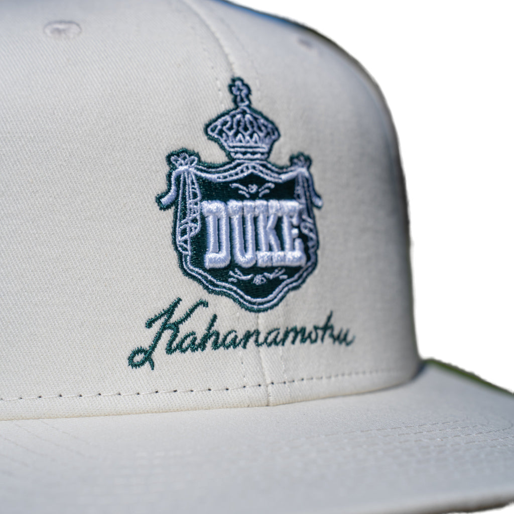 Close-up of teal DUKE royal crown crest embroidery on ivory cap