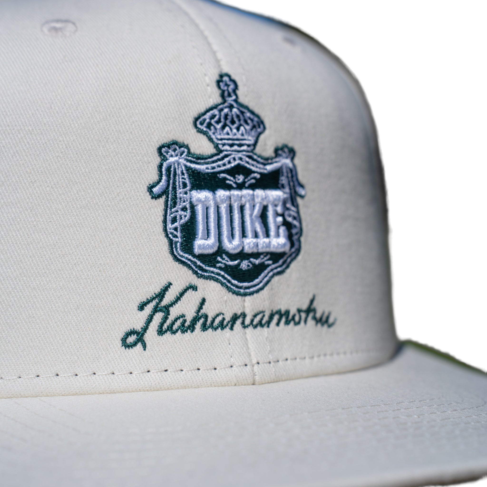 Close-up of teal DUKE royal crown crest embroidery on ivory cap