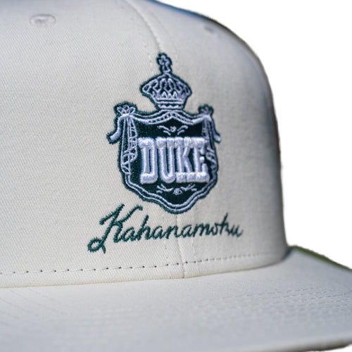 Close-up of teal DUKE royal crown crest embroidery on ivory cap