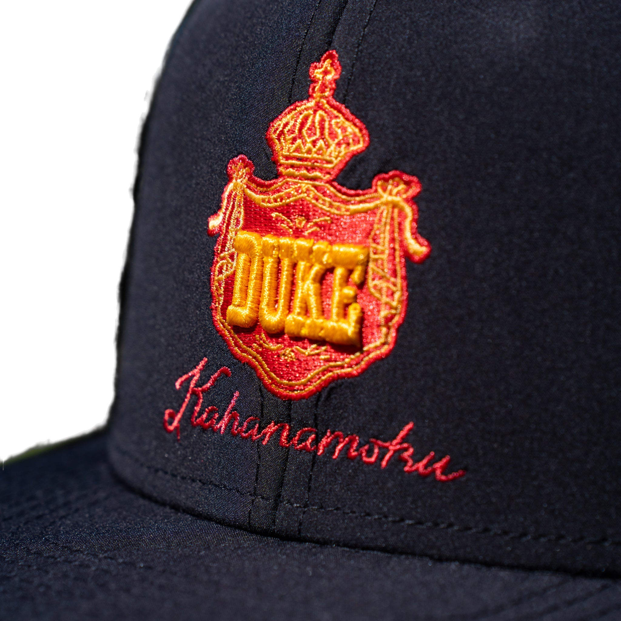 Close-up of red and gold DUKE royal crown crest embroidery on navy cap