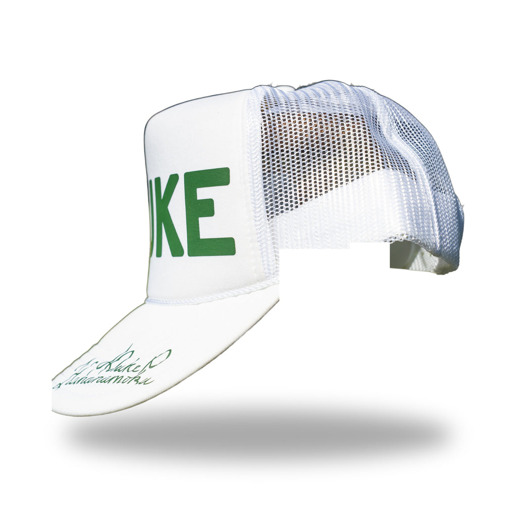 Angled rear view of white DUKE trucker hat with signature visible on the curved brim